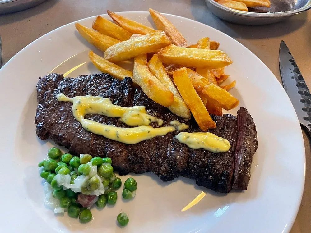 A steak at The Devonshire, sliced across the grain and topped with a ribbon of bearnaise, with thick-cut chips and buttered peas