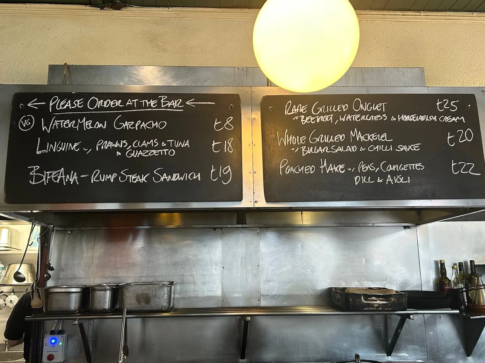 A blackboard menu at The Eagle, handwritten in chalk, listing a rump steak sandwich and other daily specials