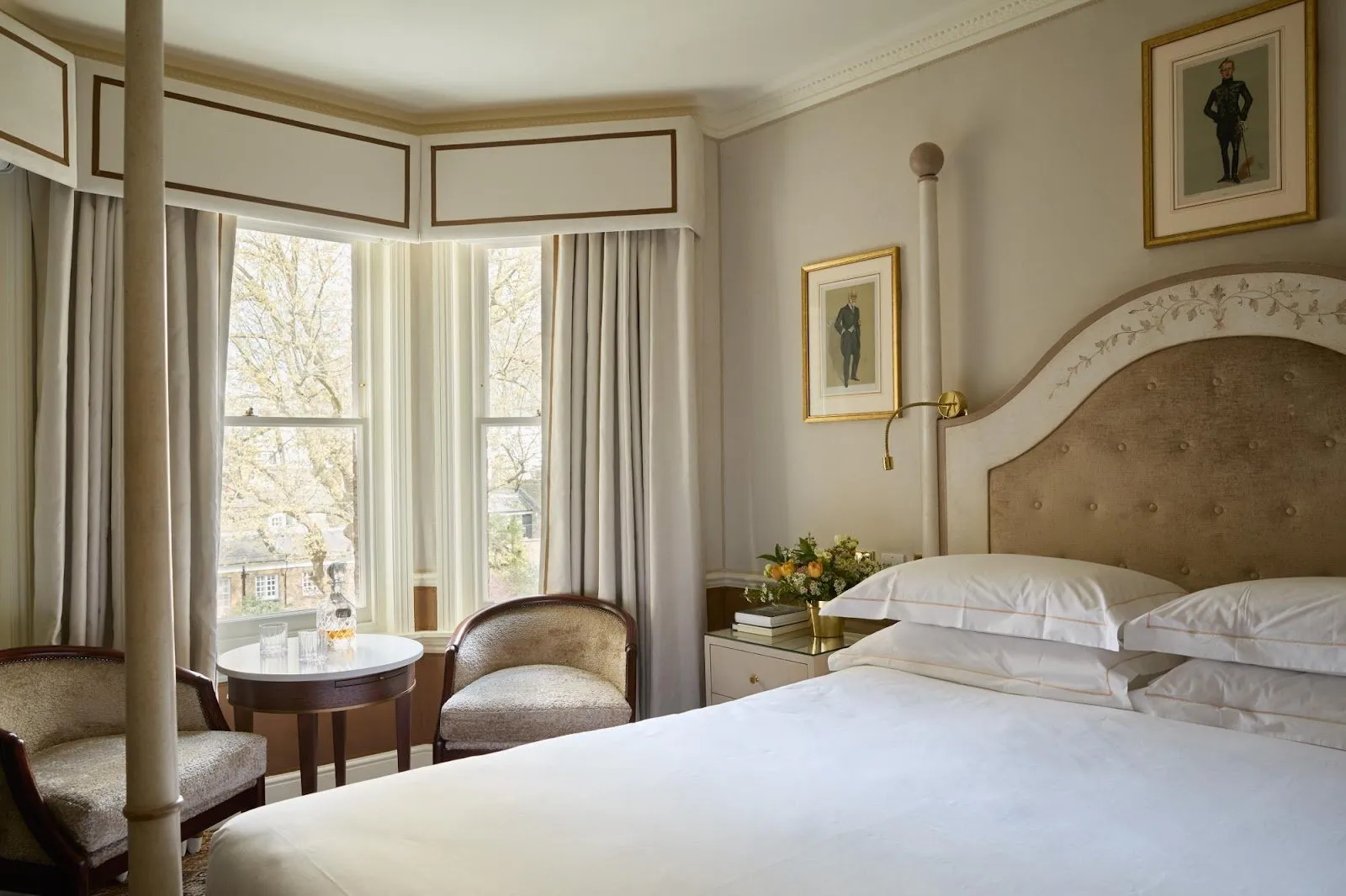 A four-poster bedroom at The Egerton House Hotel with a bay window over the garden square and gilt-framed prints