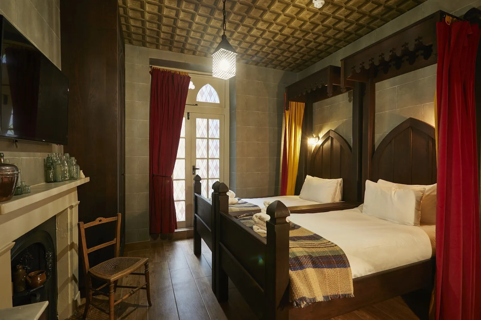The Wizard Chamber at the Georgian House Hotel with four-poster wooden beds, stone-effect arches and velvet curtains