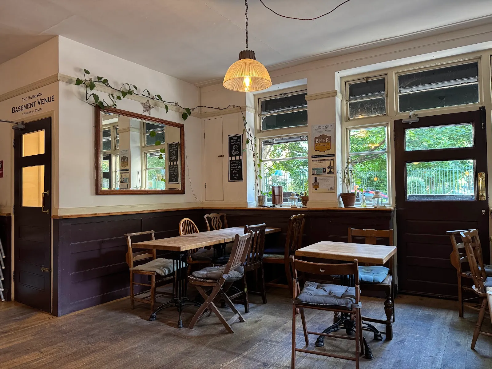 The ground-floor bar at The Harrison, with mismatched wooden chairs and a door signed The Harrison Basement Venue