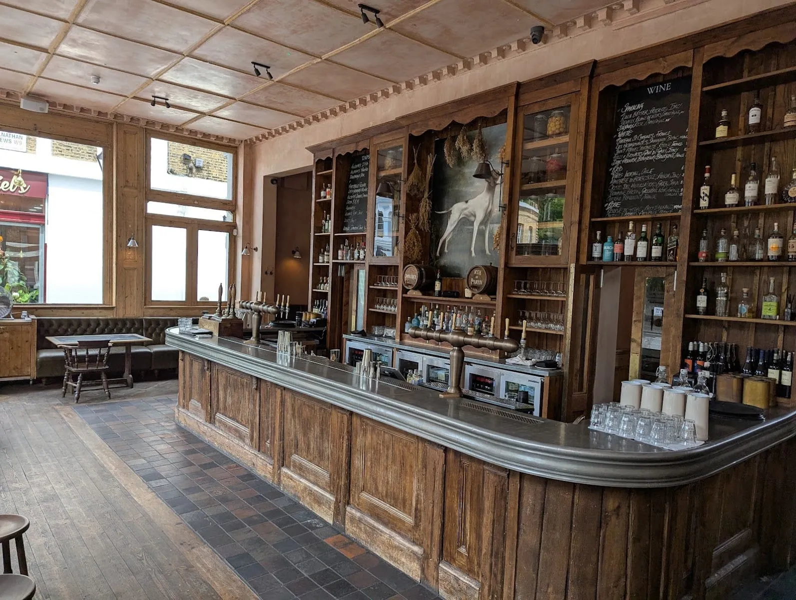The ground-floor bar at The Hero, with beer taps, shelves of spirits and a painting of a dog above the bar