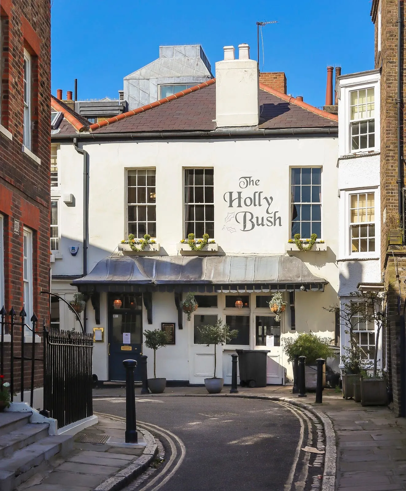 The Holly Bush pub on a quiet corner of Holly Mount, a cobbled lane in Hampstead, with window boxes and hanging baskets