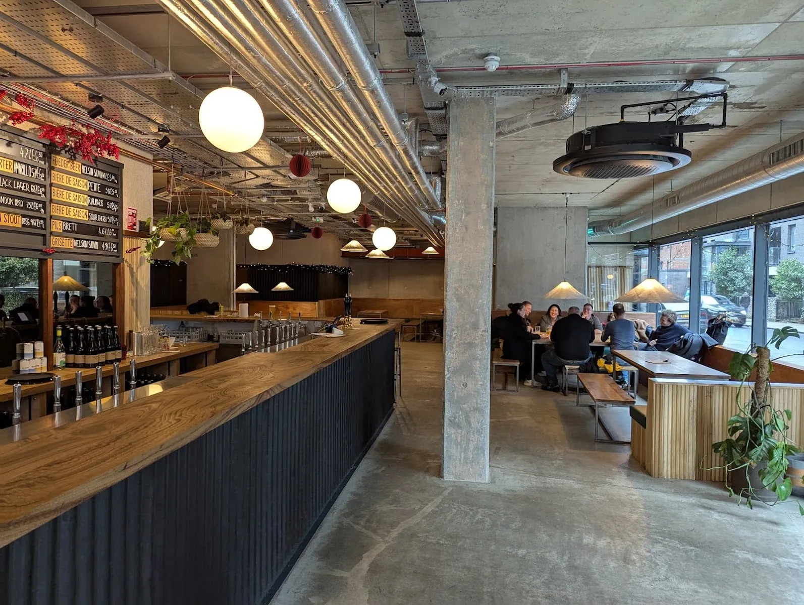 The Kernel's taproom bar, with a chalkboard listing porters, lagers and saisons beneath rows of globe pendant lights