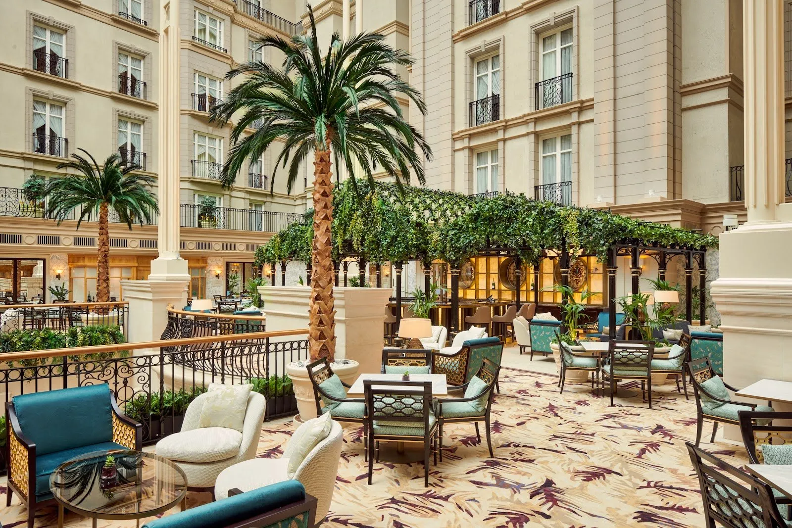 The glass-roofed Winter Garden atrium at The Landmark London with tall palm trees, dining tables and courtyard balconies