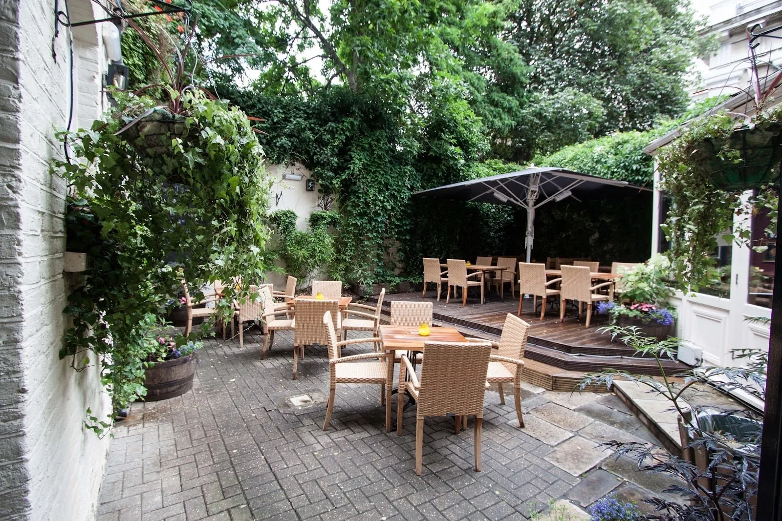 The ivy-walled garden at The Mitre, with wicker chairs and a raised wooden deck
