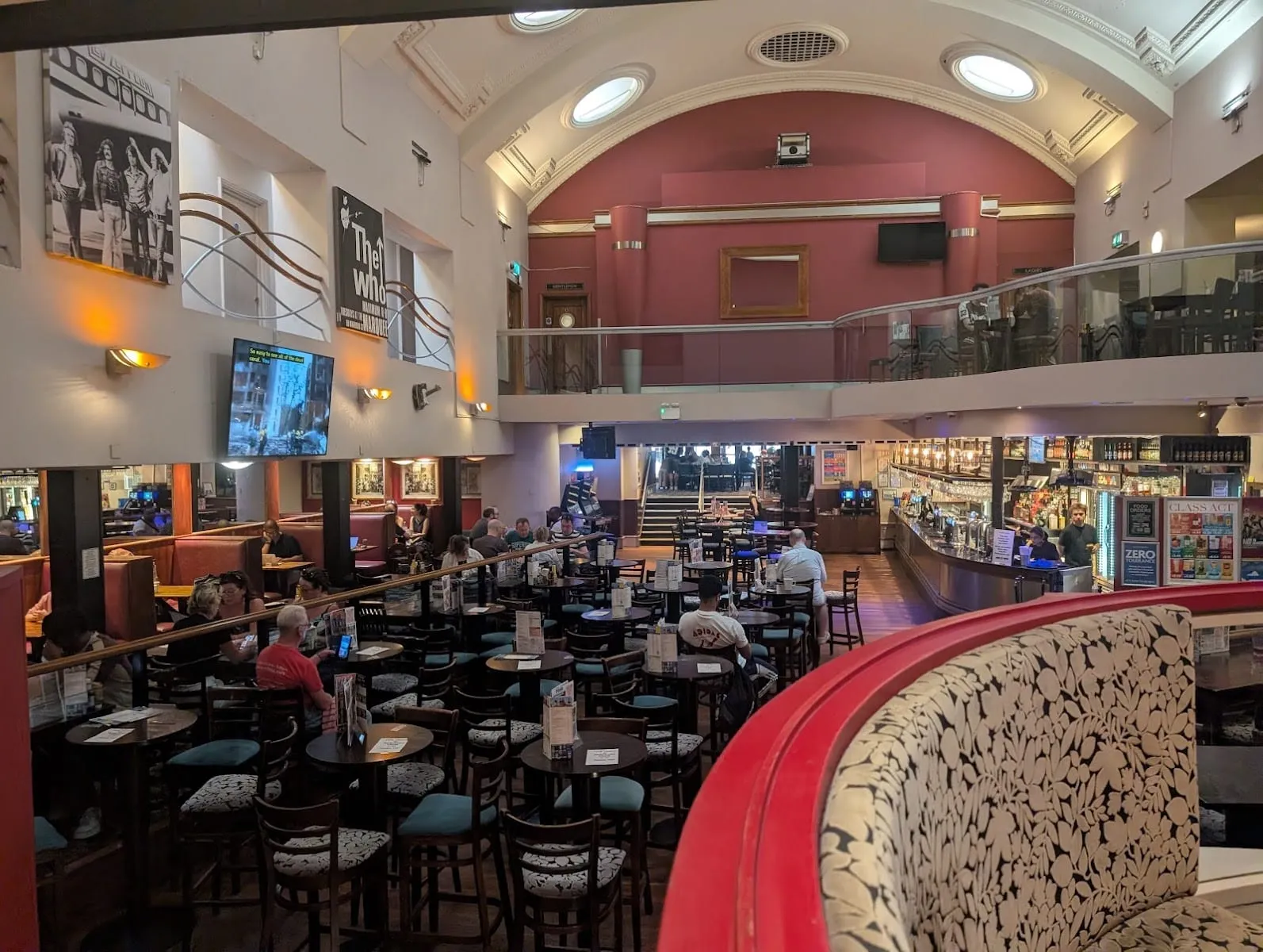 The double-height former cinema auditorium inside The Montagu Pyke, with a barrel-vaulted ceiling, round windows and framed rock posters on the walls
