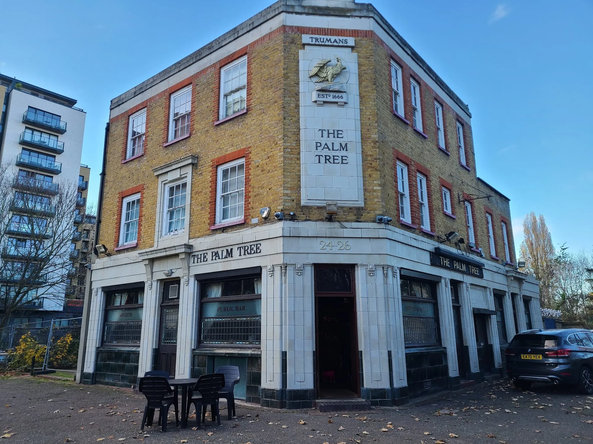 The Palm Tree's brick corner exterior in Bow, with a carved stone name plaque and a Truman's brewery eagle emblem