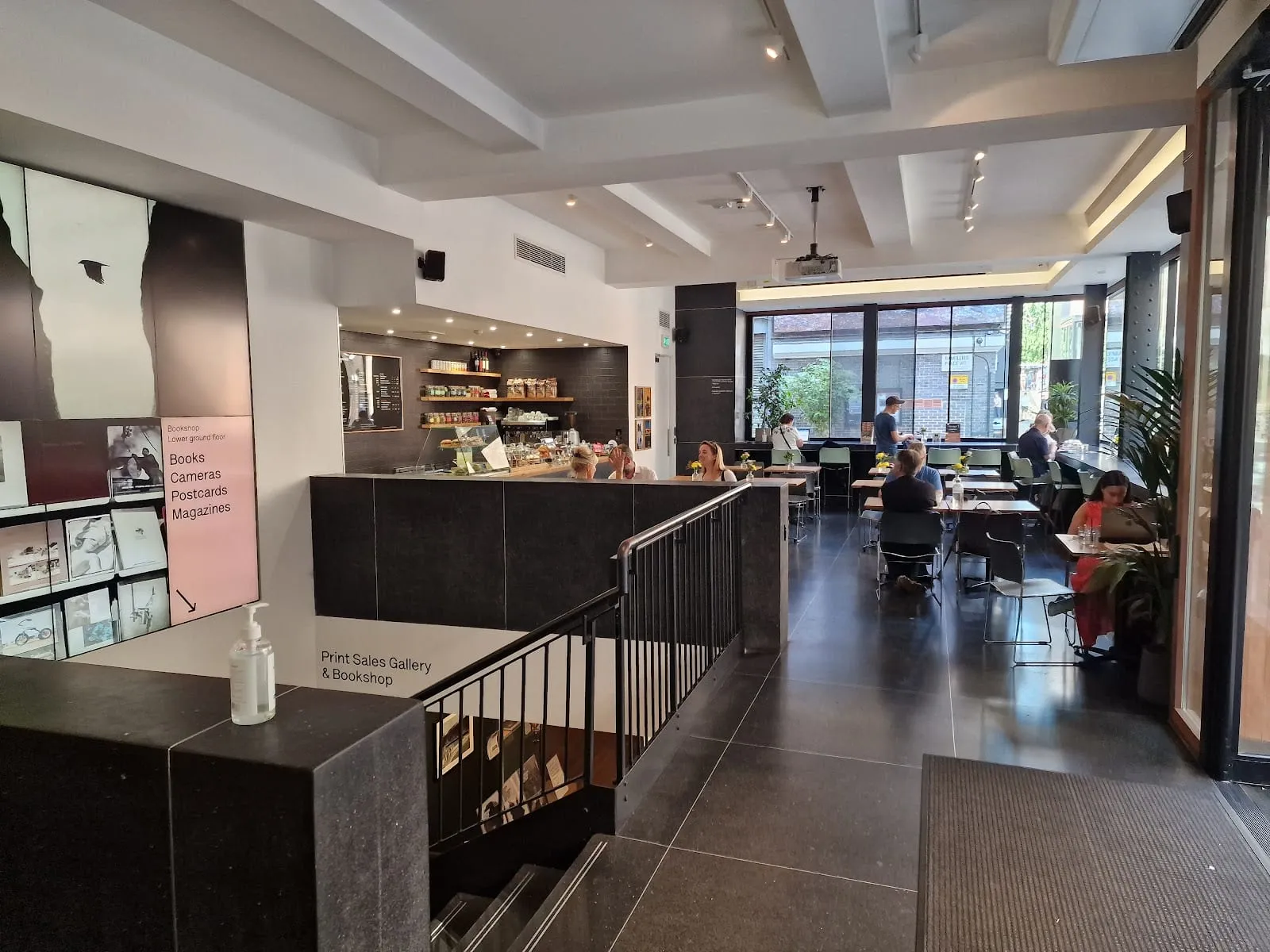 The ground floor of the Photographers' Gallery with signage for the Print Sales Gallery and Bookshop, and a small café with a few tables in the background