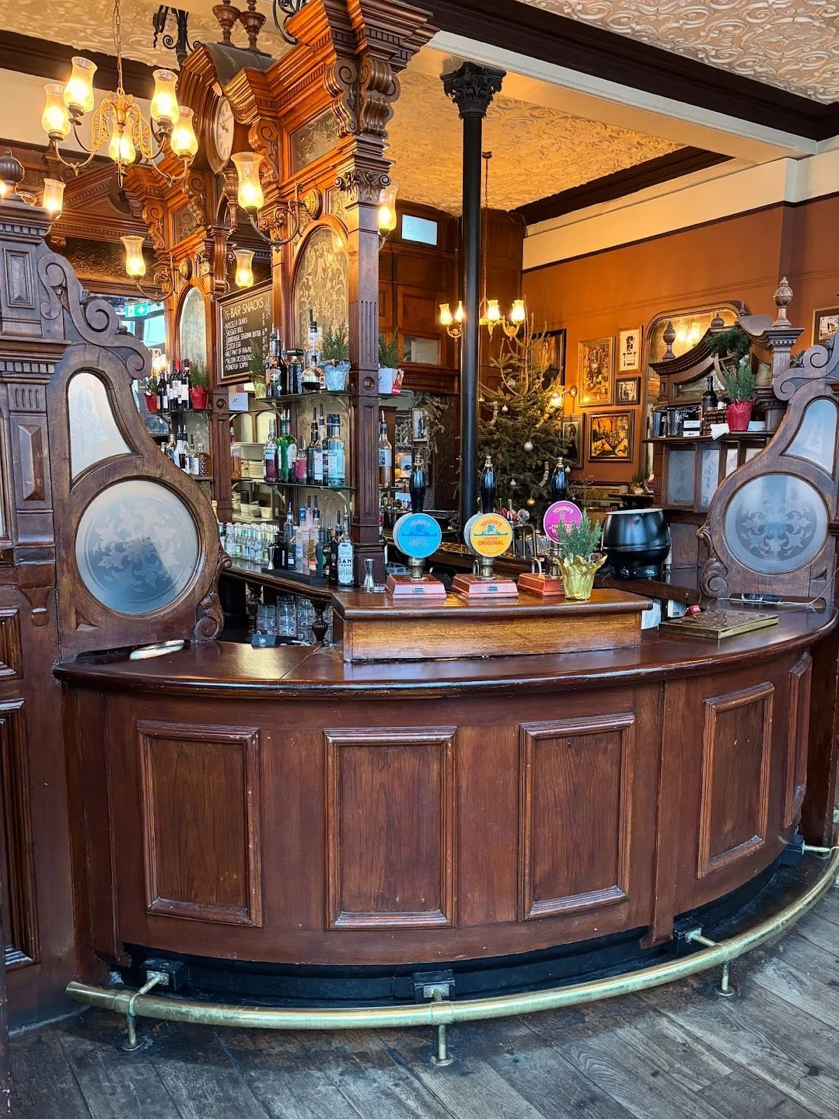 The curved wooden bar at The Prince Alfred, with etched-glass snob screens on carved frames either side of the beer pumps