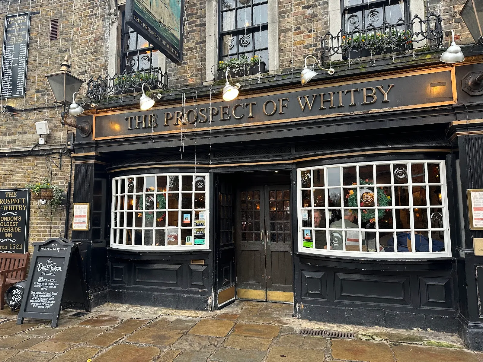 The black and gold frontage of the Prospect of Whitby on Wapping Wall, with a chalkboard naming its Devil's Tavern history