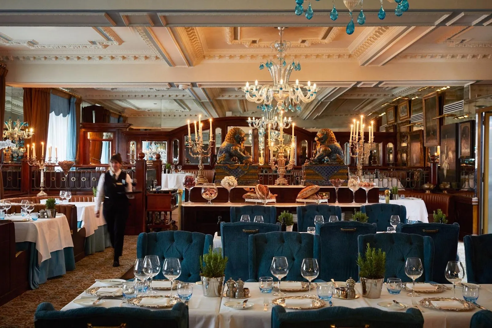The restaurant at The Rubens at the Palace, with striped booths, candelabra and a pair of Chinese guardian lion statues