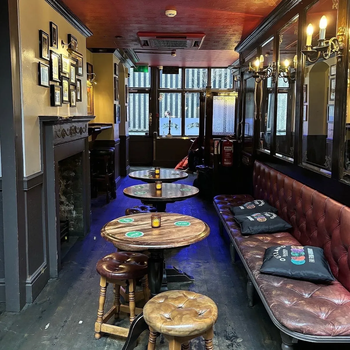 A quiet corner inside The Shaston Arms, with framed pictures on the wall, a fireplace and leather banquette seating