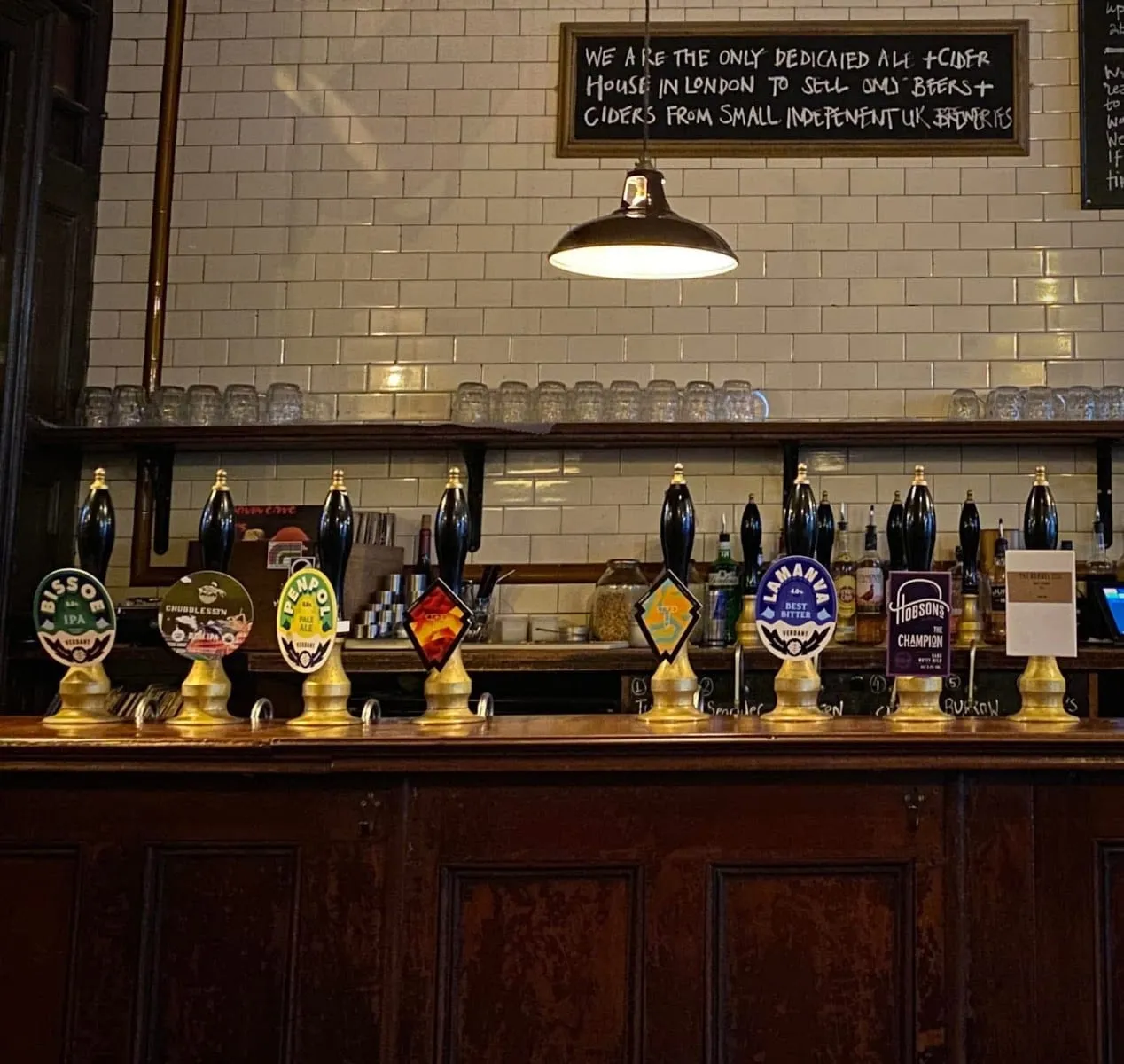 A row of handpumps at the Southampton Arms, below a sign reading that it is the only dedicated ale and cider house in London selling only beers and ciders from small independent UK breweries