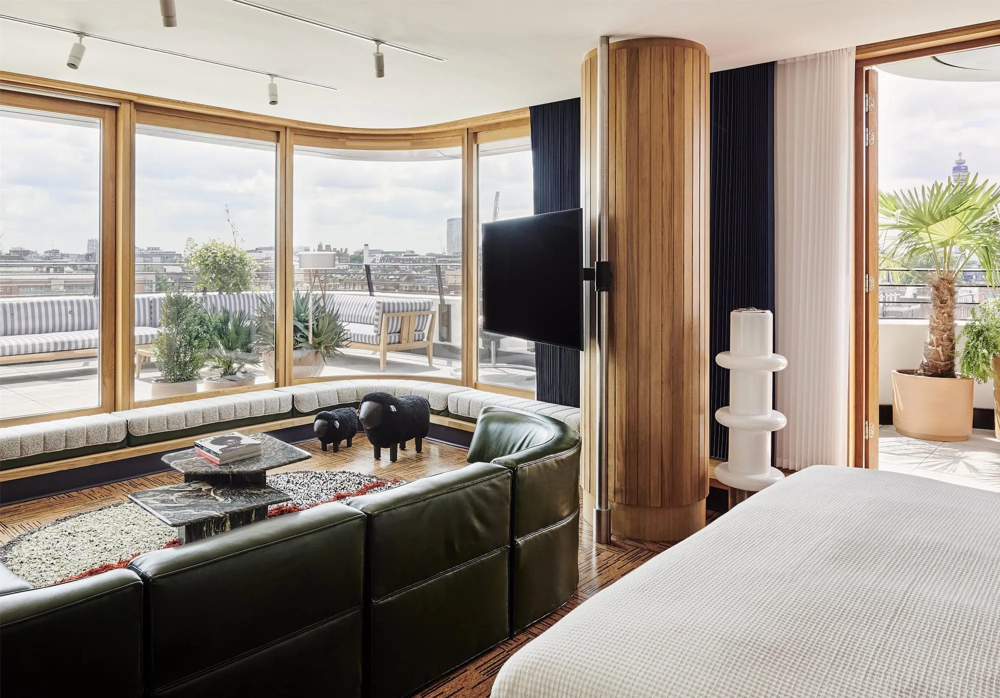 A suite at The Standard, London, with a curved floor-to-ceiling window bay, a built-in window seat and doors opening onto a private terrace