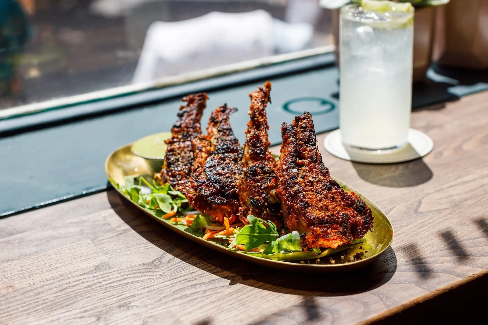 Charred chicken lollipops with a green chutney, served on a gold plate at The Tamil Prince