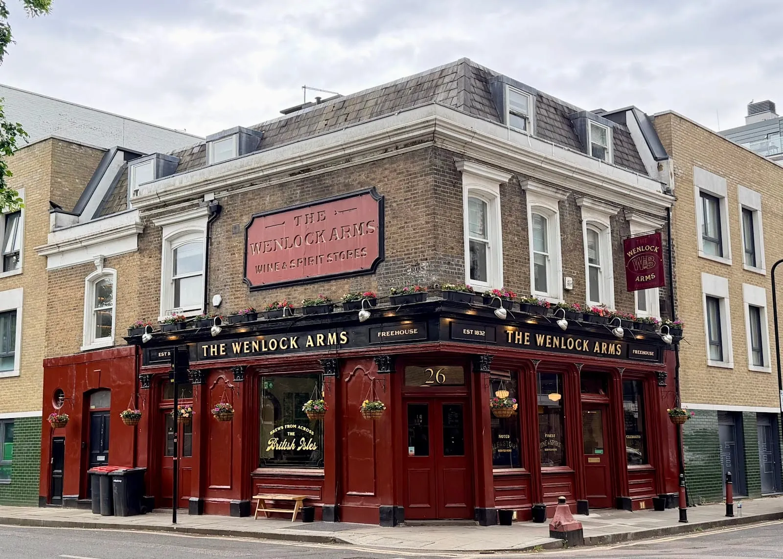 The Wenlock Arms' red-fronted corner building on Wenlock Road, Hoxton, with hanging flower baskets and a Freehouse sign