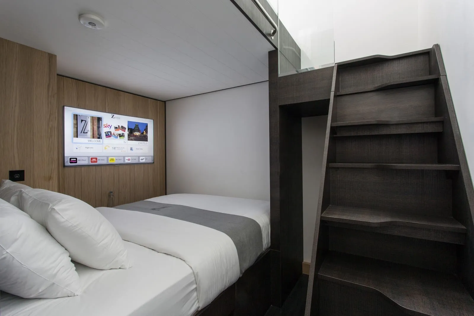 A room at The Z Hotel Shoreditch with a double bed and a wooden staircase up to a second bed above it