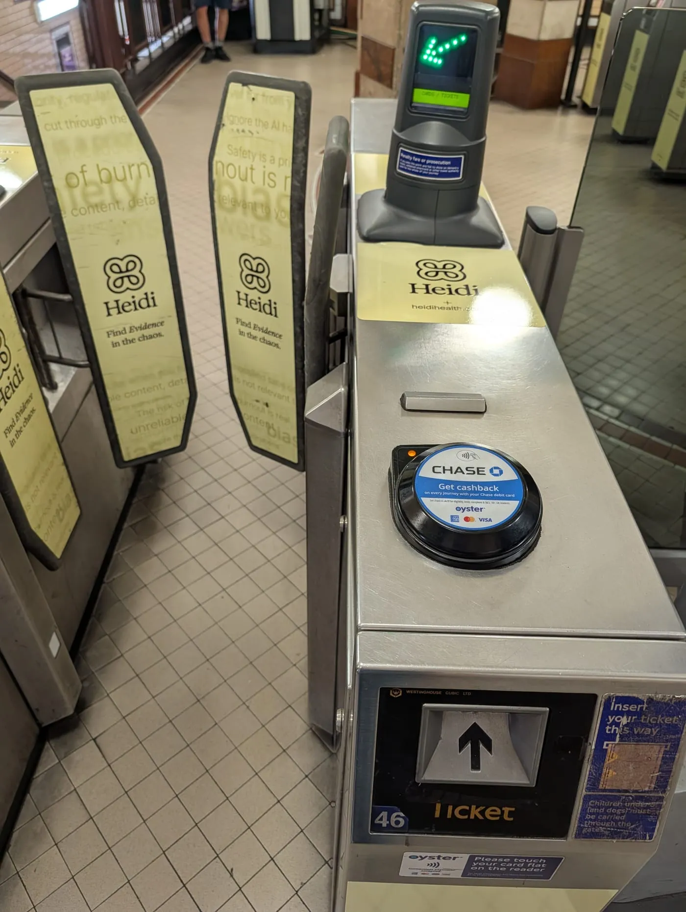 Ticket barriers at a London Underground station, with a yellow contactless reader on the gate