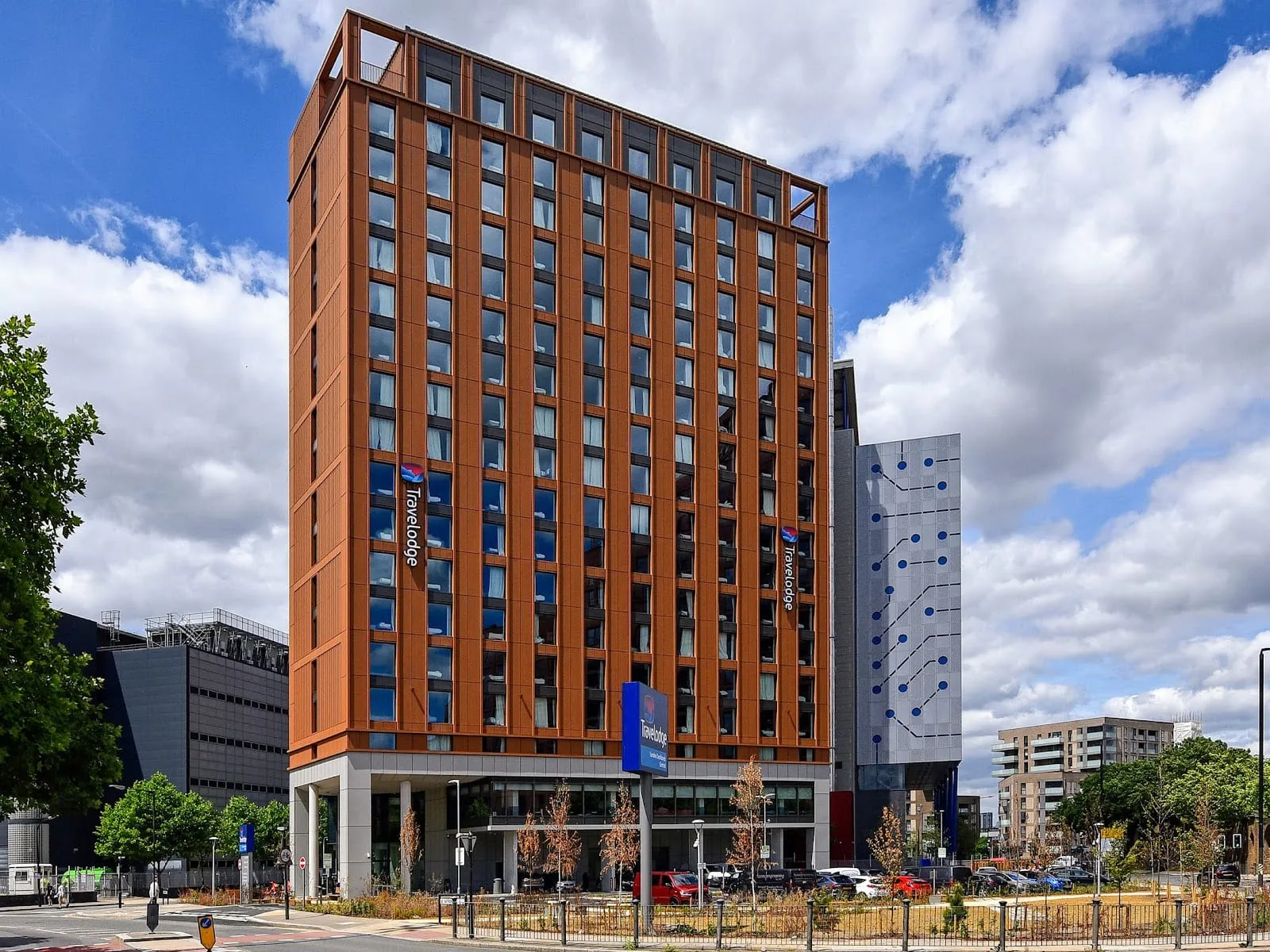 Travelodge London Docklands Central, a tall new-build tower clad in orange panels beside a main road