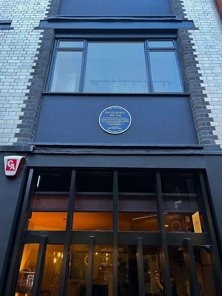 A blue plaque on a dark-painted Soho shopfront reading David Bowie 1947-2016, noting that Hunky Dory, The Rise and Fall of Ziggy Stardust and the song Space Oddity were recorded at Trident Studios