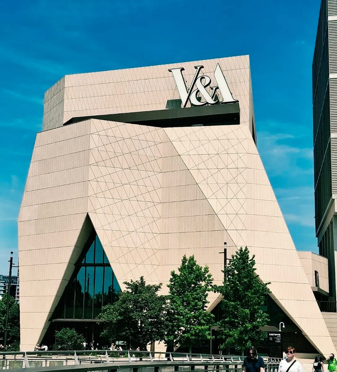 The angular pale stone facade of V&A East Museum on East Bank, with a large V&A logo mounted near the roofline