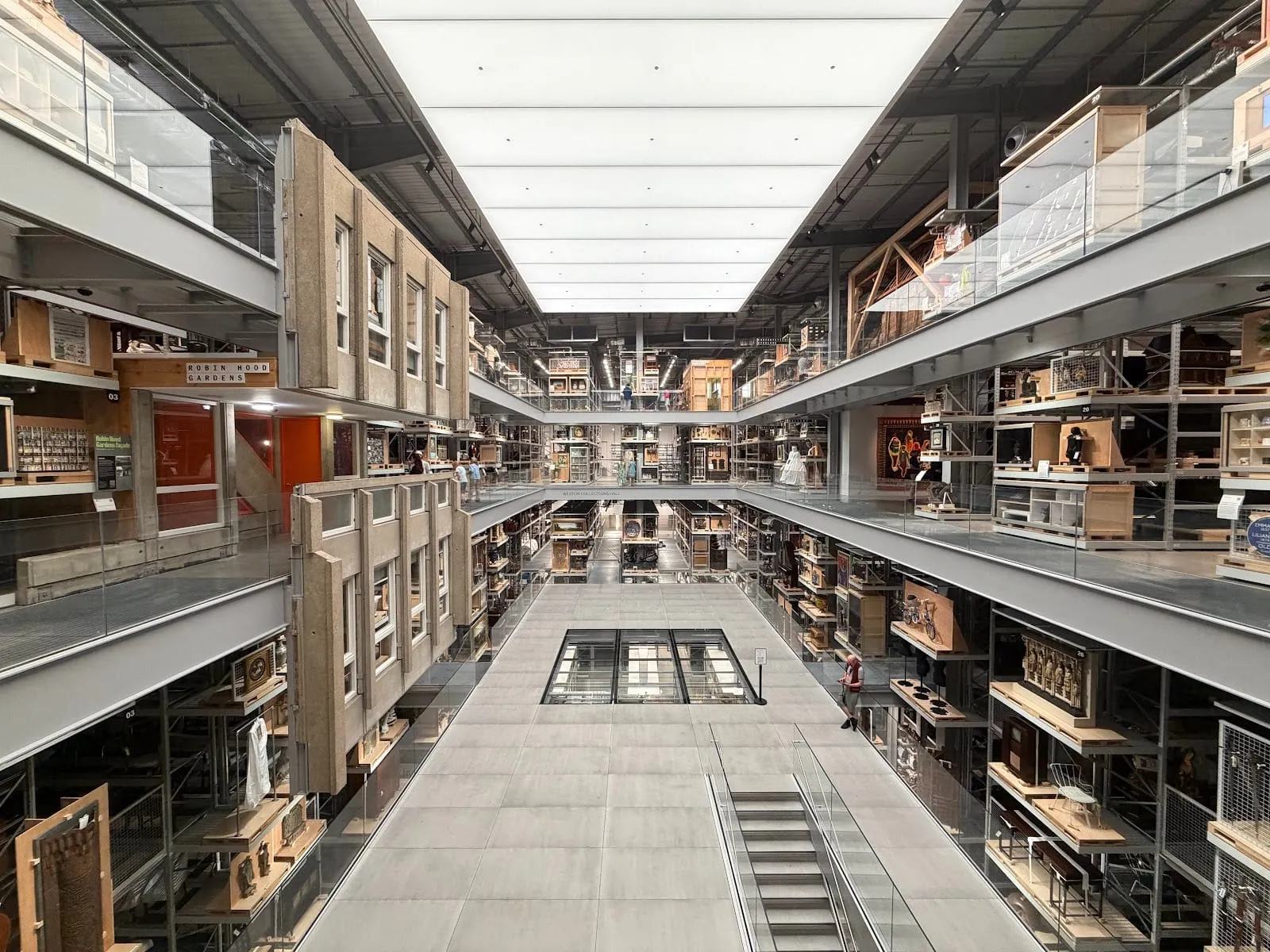 A multi-storey warehouse hall at V&A East Storehouse with open metal racking on both sides holding objects, models and furniture