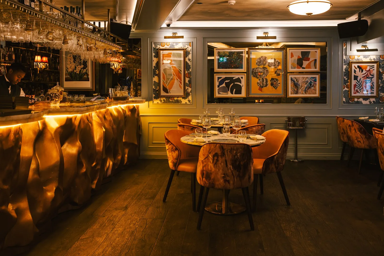 The dining room at Vatavaran in Knightsbridge with an undulating backlit gold bar and warm velvet armchairs