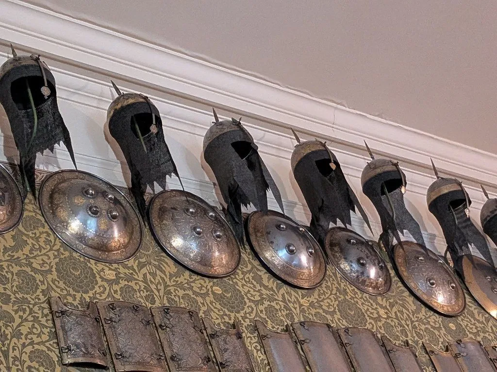 A row of medieval helmets and shields mounted along a wall in the Wallace Collection