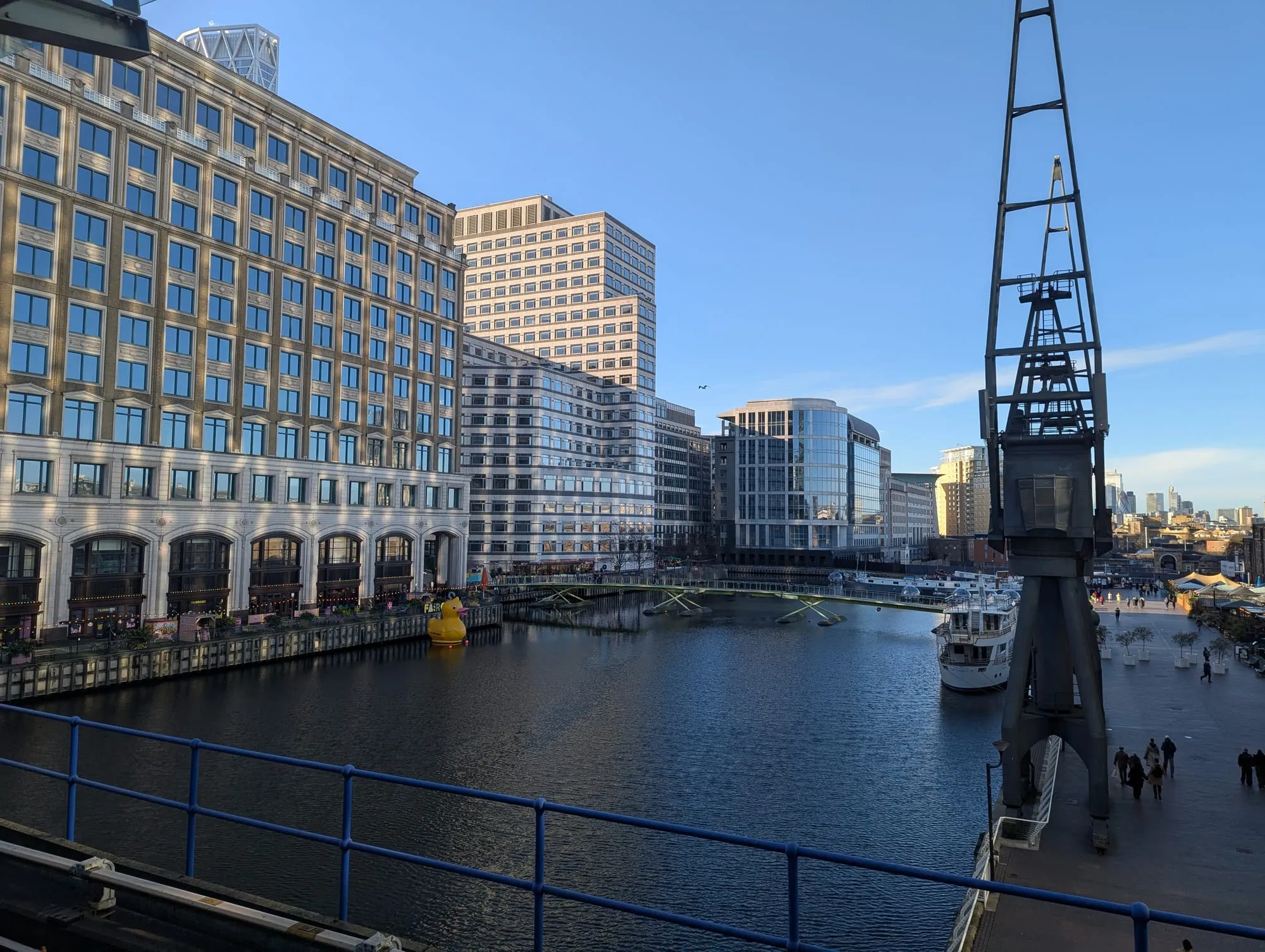 Georgian warehouses and a preserved dockside crane at West India Quay, with the City skyline in the distance
