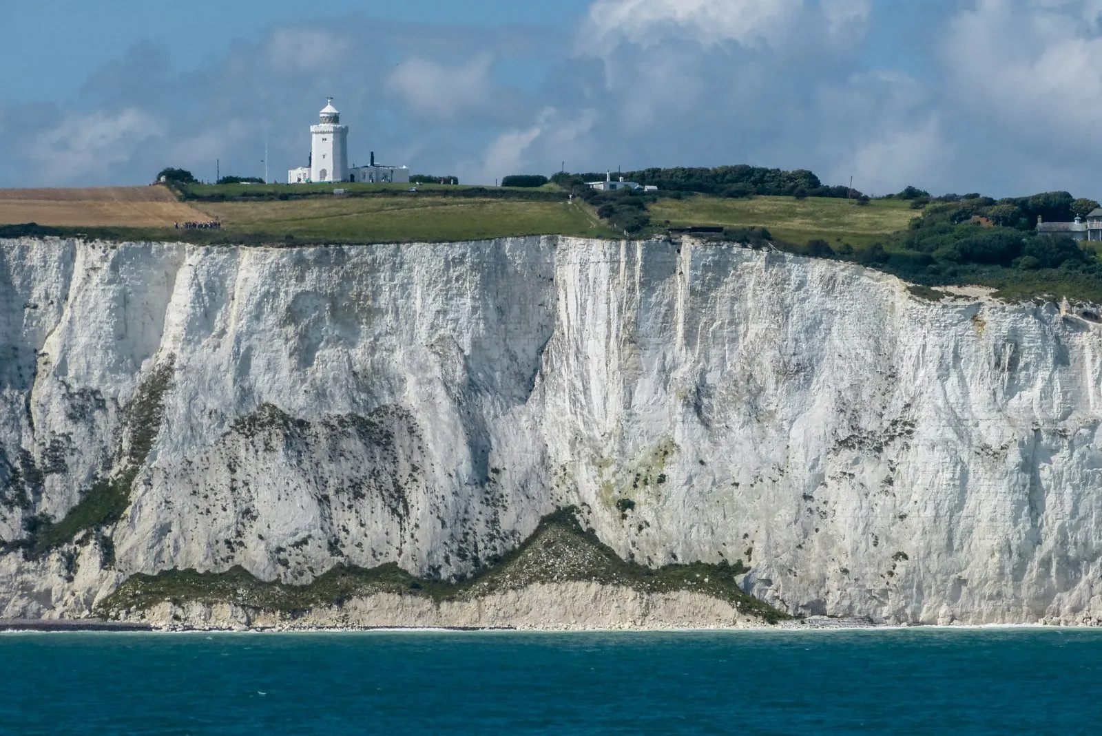 The white chalk cliffs east of Dover topped with grassland, South Foreland Lighthouse standing on the clifftop above the sea