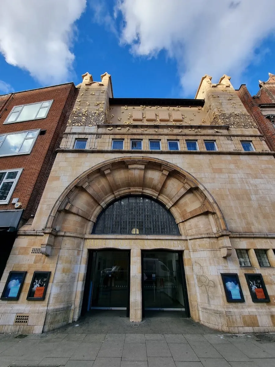The Art Nouveau stone facade of Whitechapel Gallery with a large arched entrance and Whitechapel Art Gallery carved in gold lettering above the doors