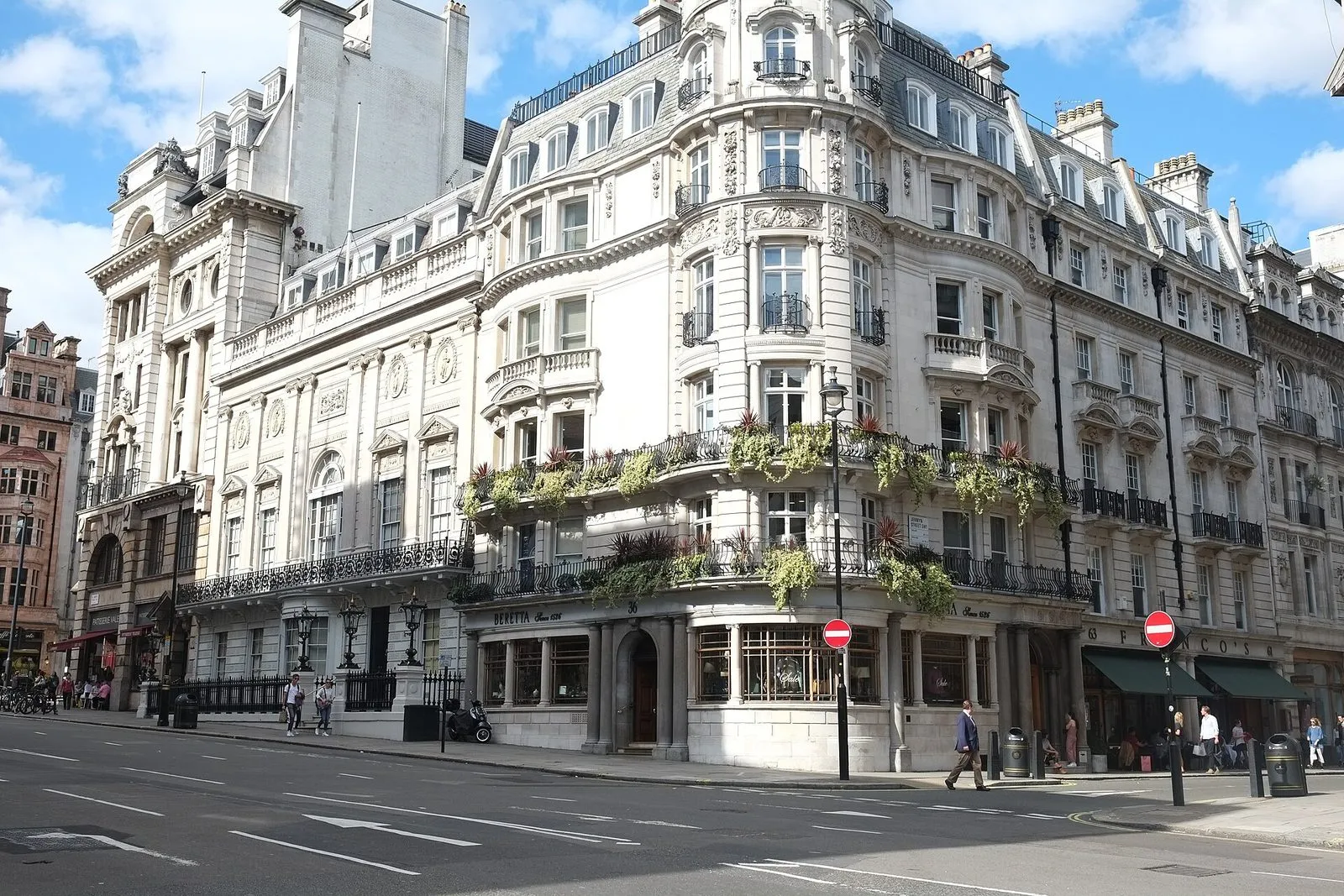 White's on St James's Street, a white stone classical facade with lanterns and railings, beside the curved corner building on Jermyn Street