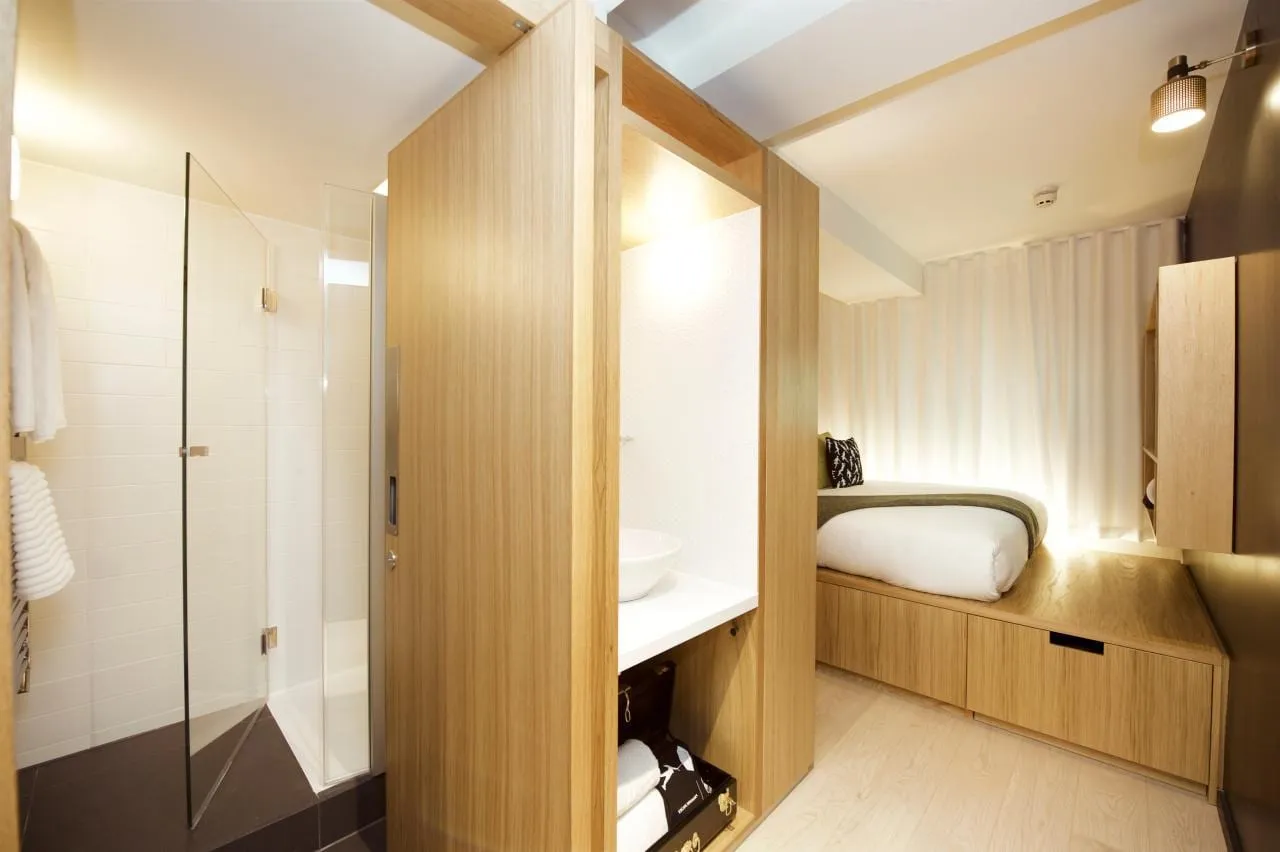 The wood-clad ensuite pod inside a Wilde Covent Garden studio, with a glass shower door and a round vessel basin