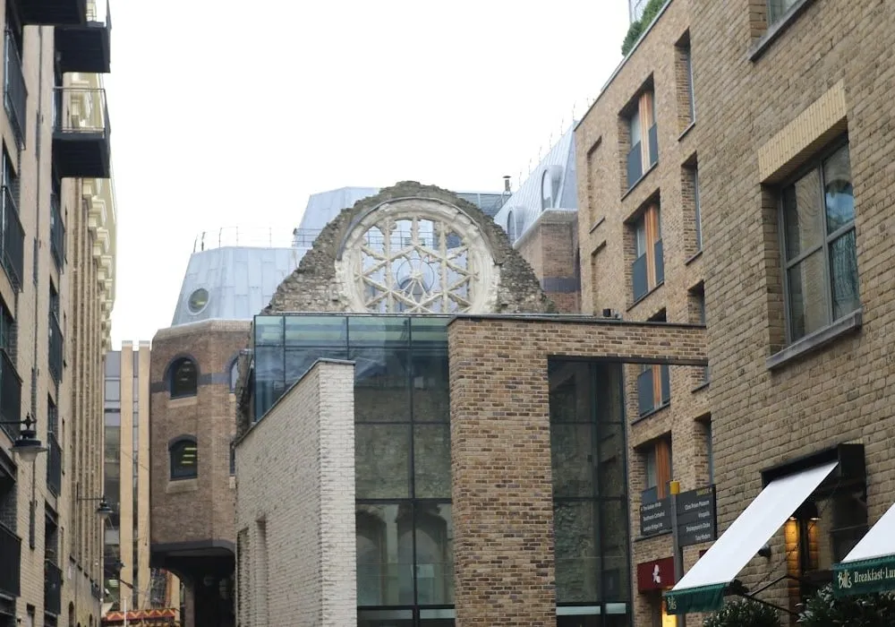 The ruined stone gable of Winchester Palace with its round rose window of stone tracery, rising above a glass and brick building on Clink Street