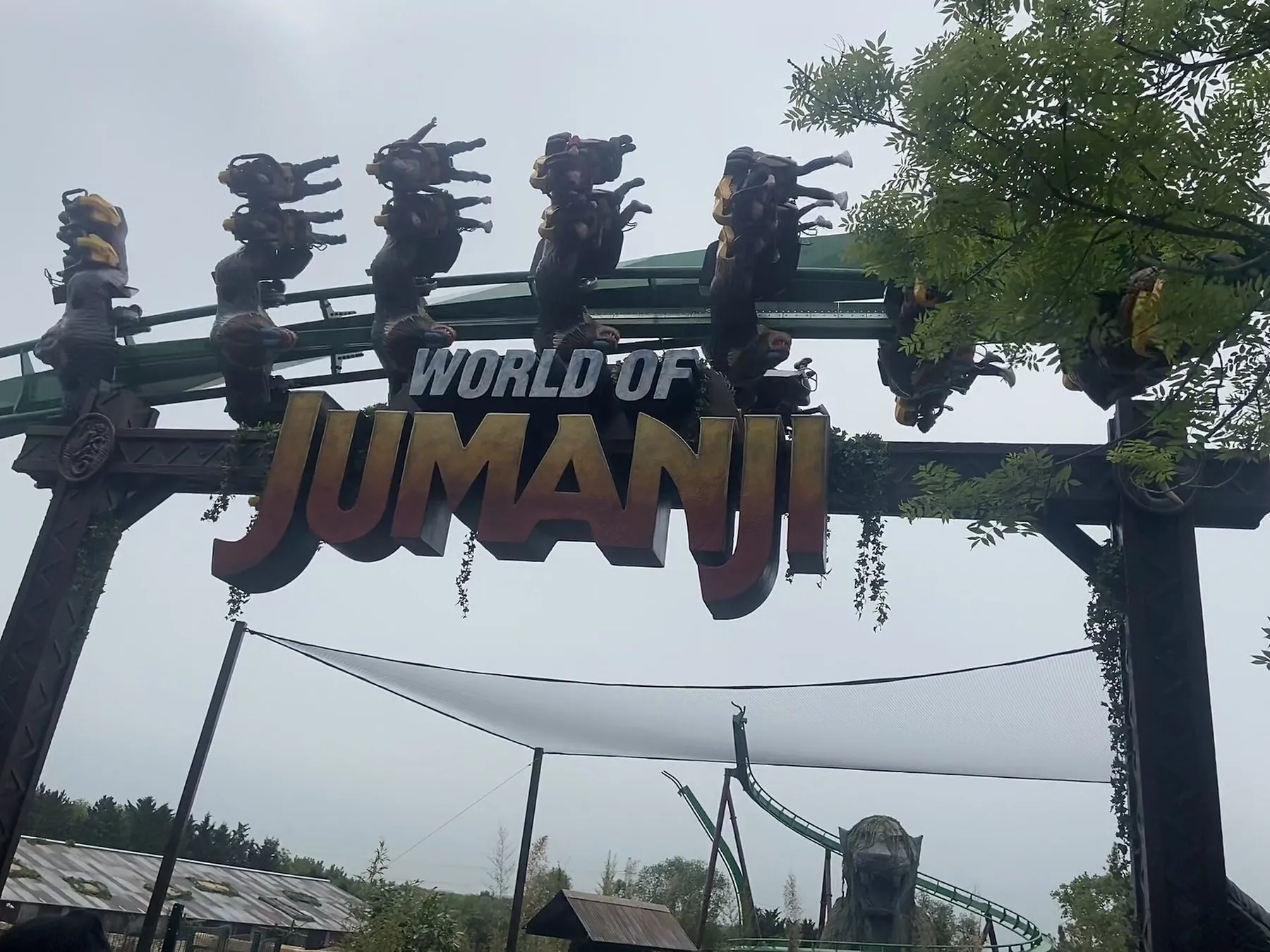 The World of Jumanji entrance arch at Chessington, with riders of Mandrill Mayhem upside down on the green coaster track above the sign