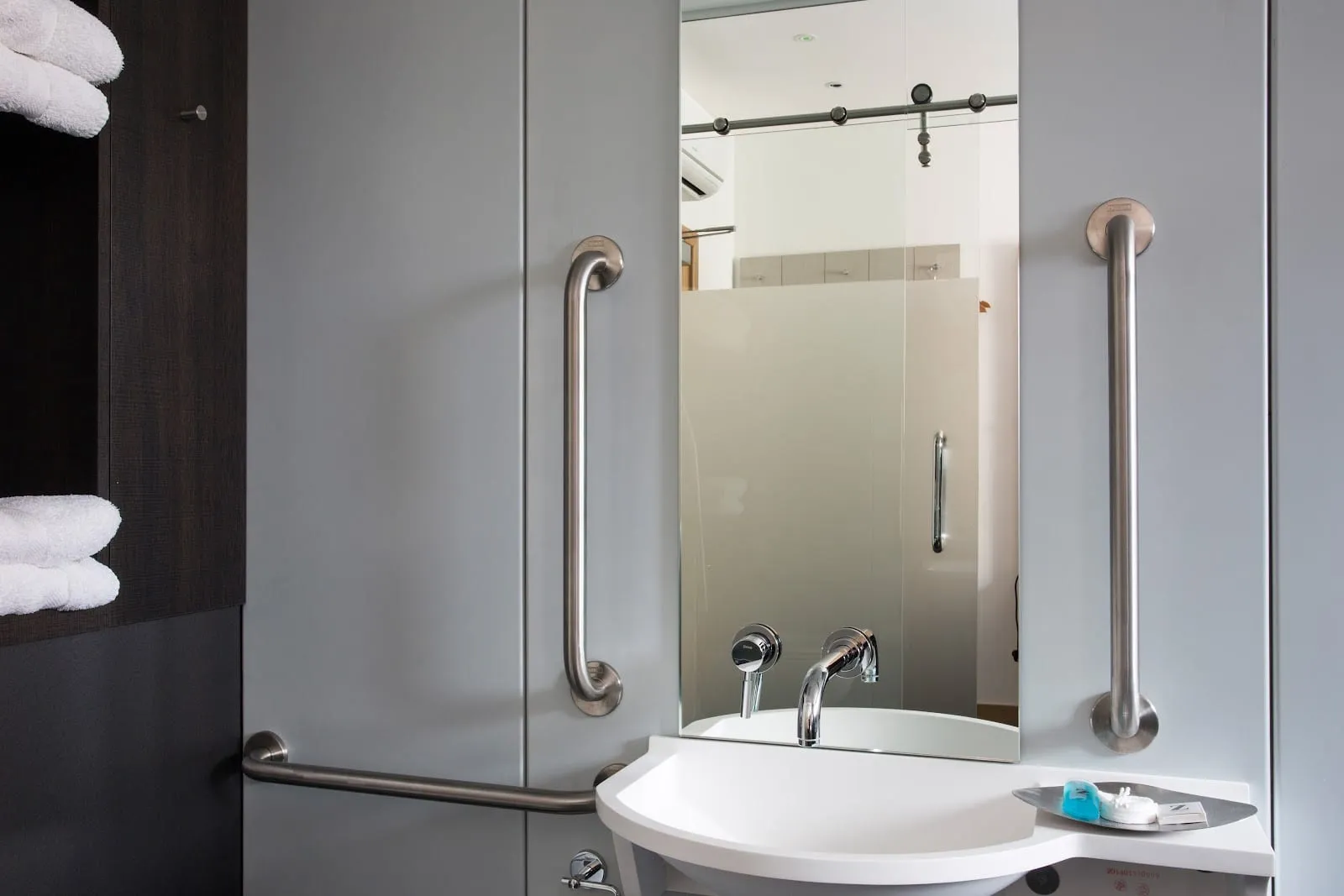 An ensuite bathroom at the Z Hotel Shoreditch, with wall-mounted grab rails either side of the mirror and sink