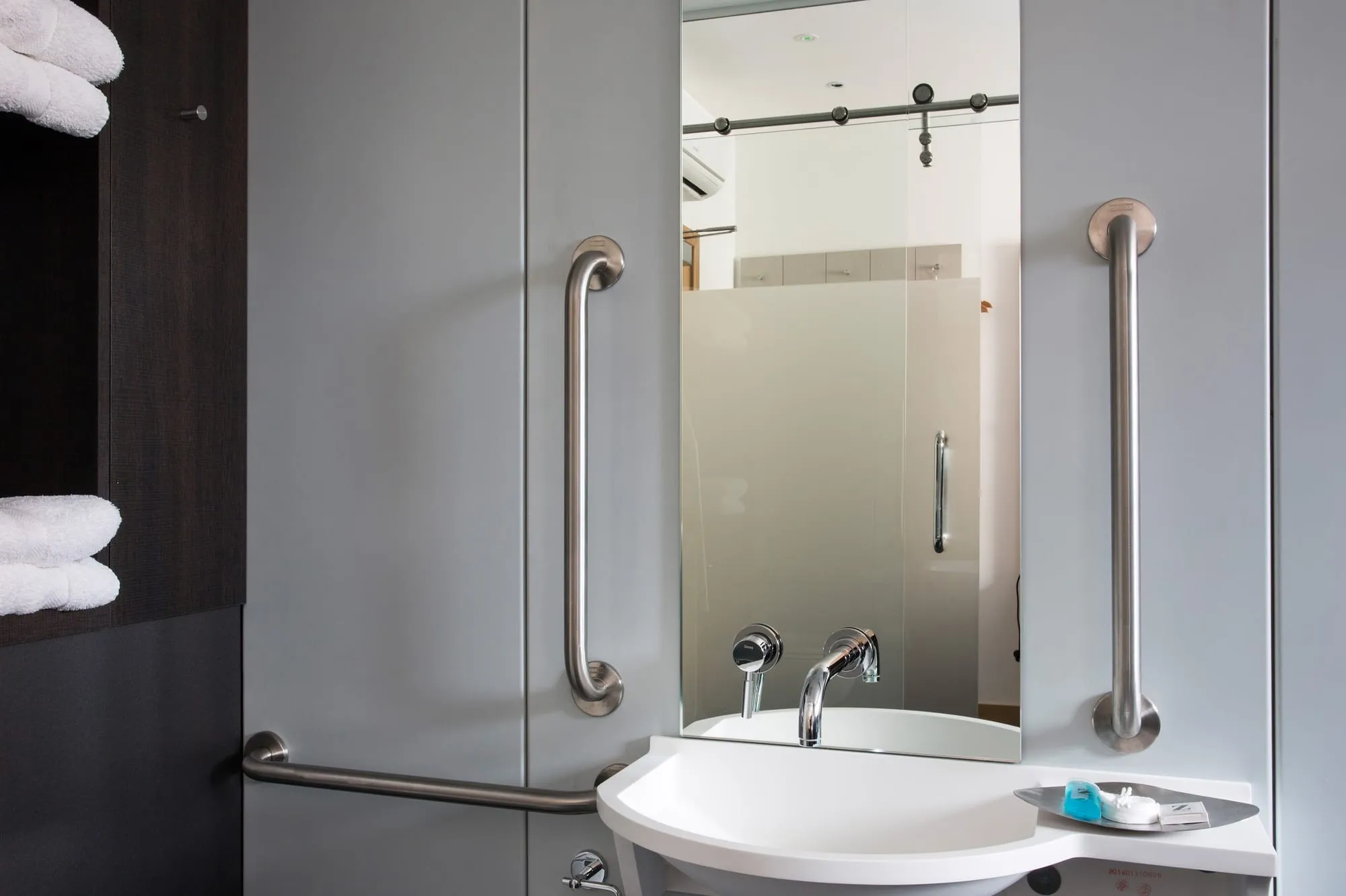 A compact ensuite bathroom at the Z Hotel Shoreditch with a sliding glass shower door and a round sink