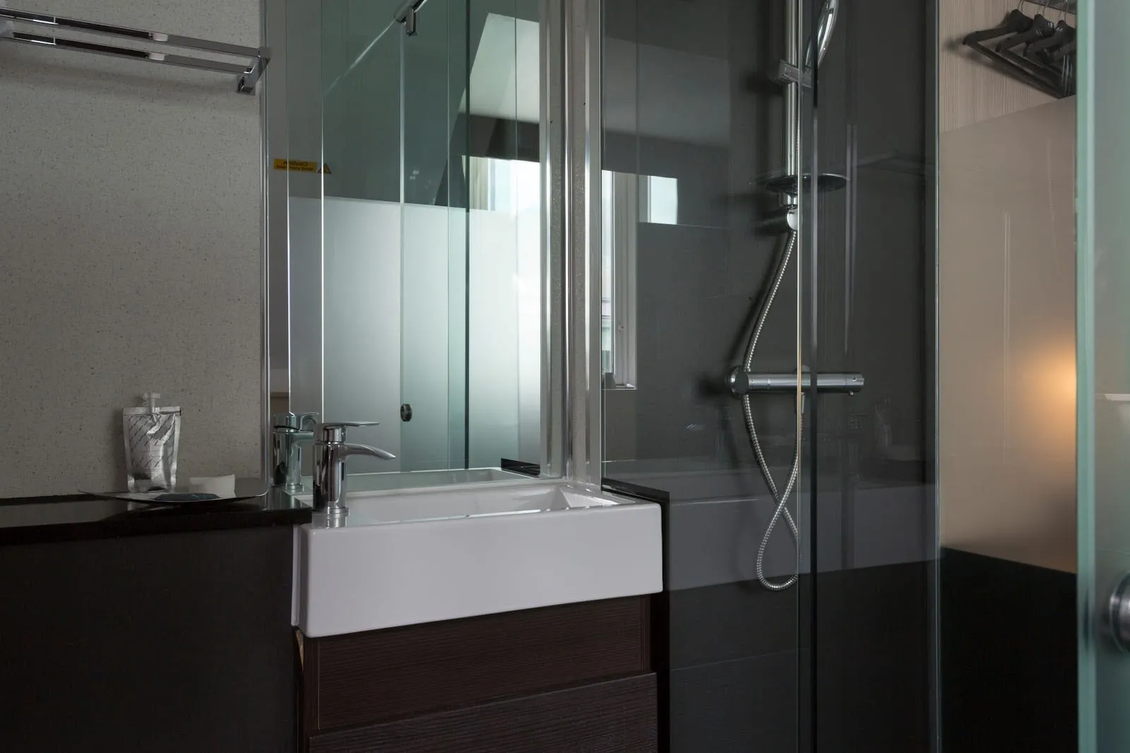 An ensuite bathroom at the Z Hotel Victoria, with a glass-walled shower and dark tiling
